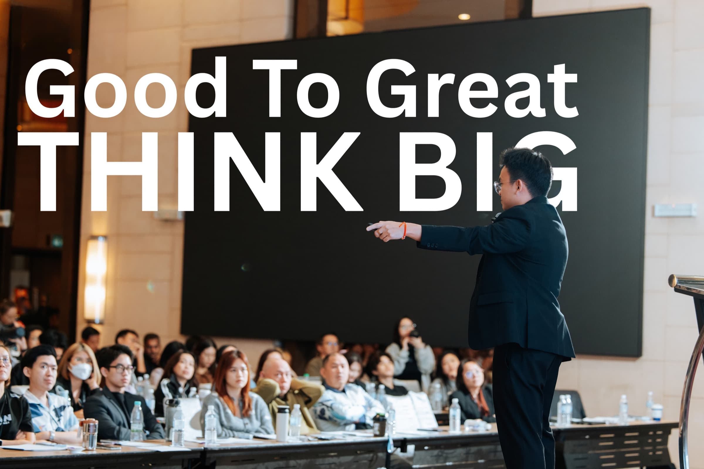Jacob Ong speaking on stage at a PropNex training: Good to Great, Think Big